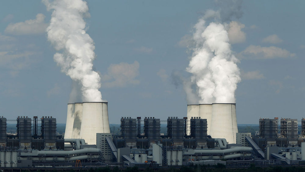 Coal power plant with two plumes of white smoke against a blue sky.